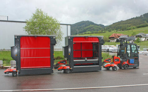 Vollautomatisierter und autonomer Outdoor-Routenzug Factory Train von Neumaier Industry mit Rollenbahn-Warenträger für die automatisierte Beladung von stationärer Fördertechnik bzw. Entladung auf stationärer Fördertechnik